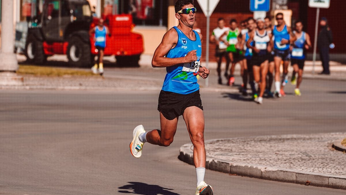 Dynamic image of a male athlete leading a marathon on a sunny day, showcasing determination and endurance.